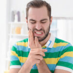 Person experiencing dental pain while brushing teetch