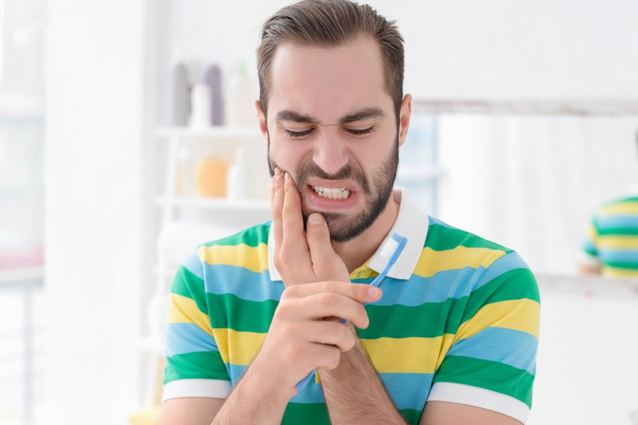 Person experiencing dental pain while brushing teetch